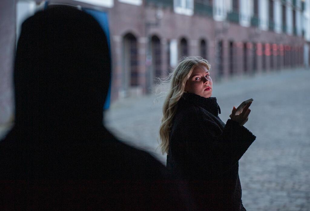 Frau mit Handy und dunkle Gestalt