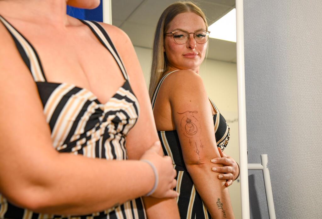 Frau betrachtet ihr Tattoo im Spiegel.